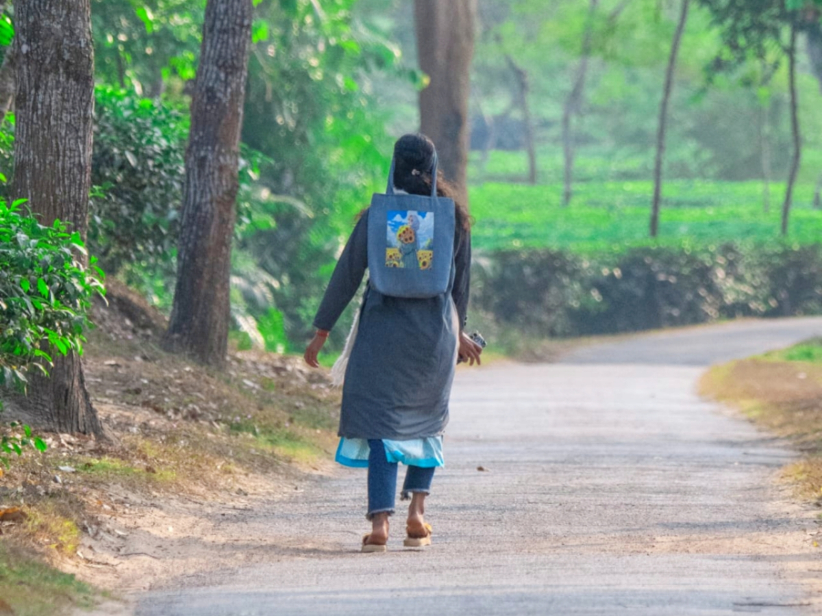 চা বাগানে রাস্তায় হেঁটে যাচ্ছে এক স্কুল পড়ুয়া শিশু। ছবি: কাজল হাজরা